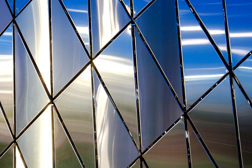 A close-up image of a building in Russia with an abstract pattern of triangular-shaped polished metal panels.