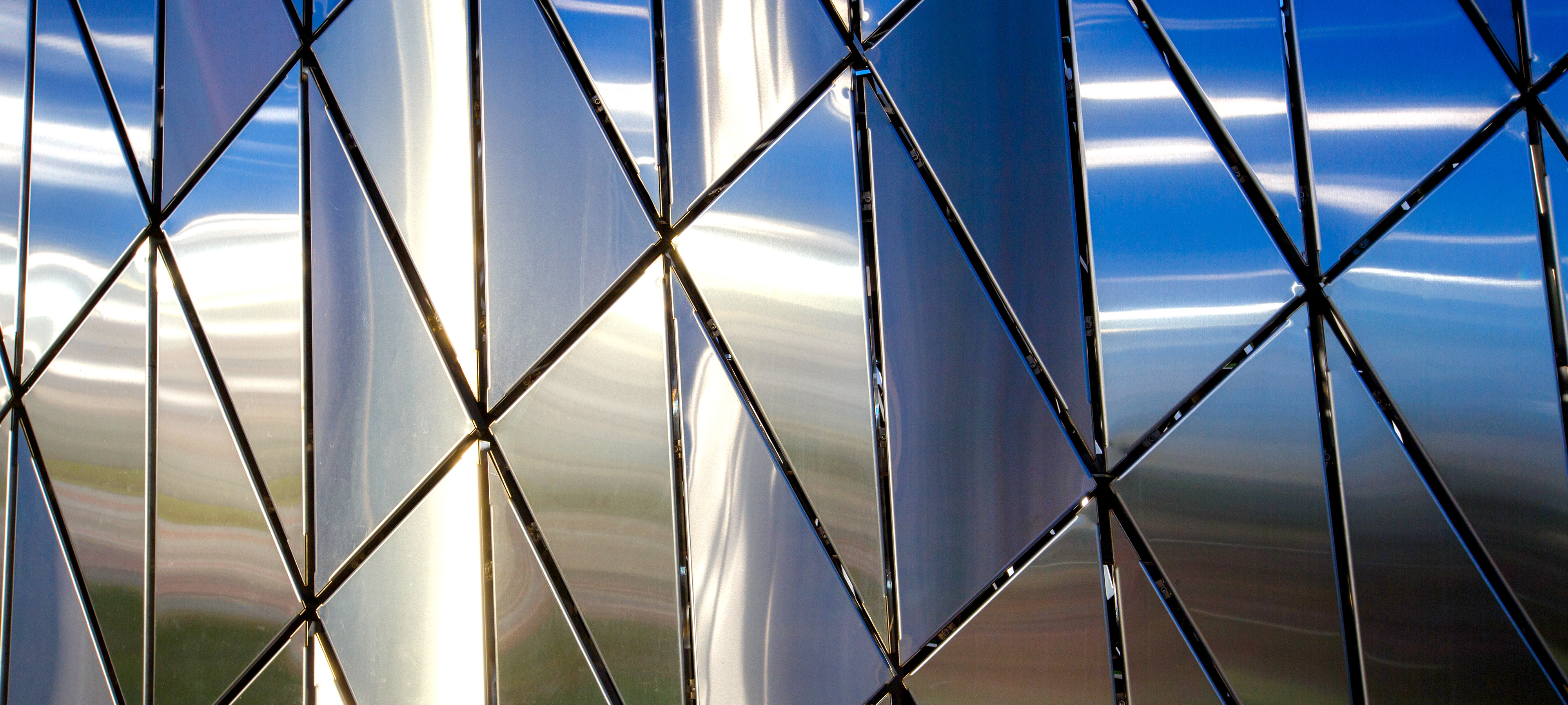 A close-up image of a building in Russia with an abstract pattern of triangular-shaped polished metal panels.