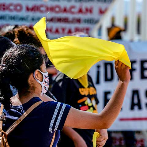 A woman flutters a yellow handkerchief during a protest of migrants and human rights activists at the San Ysidro border crossing port in Tijuana, Mexico, in October 2020. 