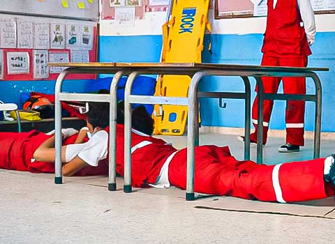 A photo of volunteers at the Tunisian Red Crescent crawling under metal barriers as part of first aid training. COVID-19 has made life-saving skills critically important.