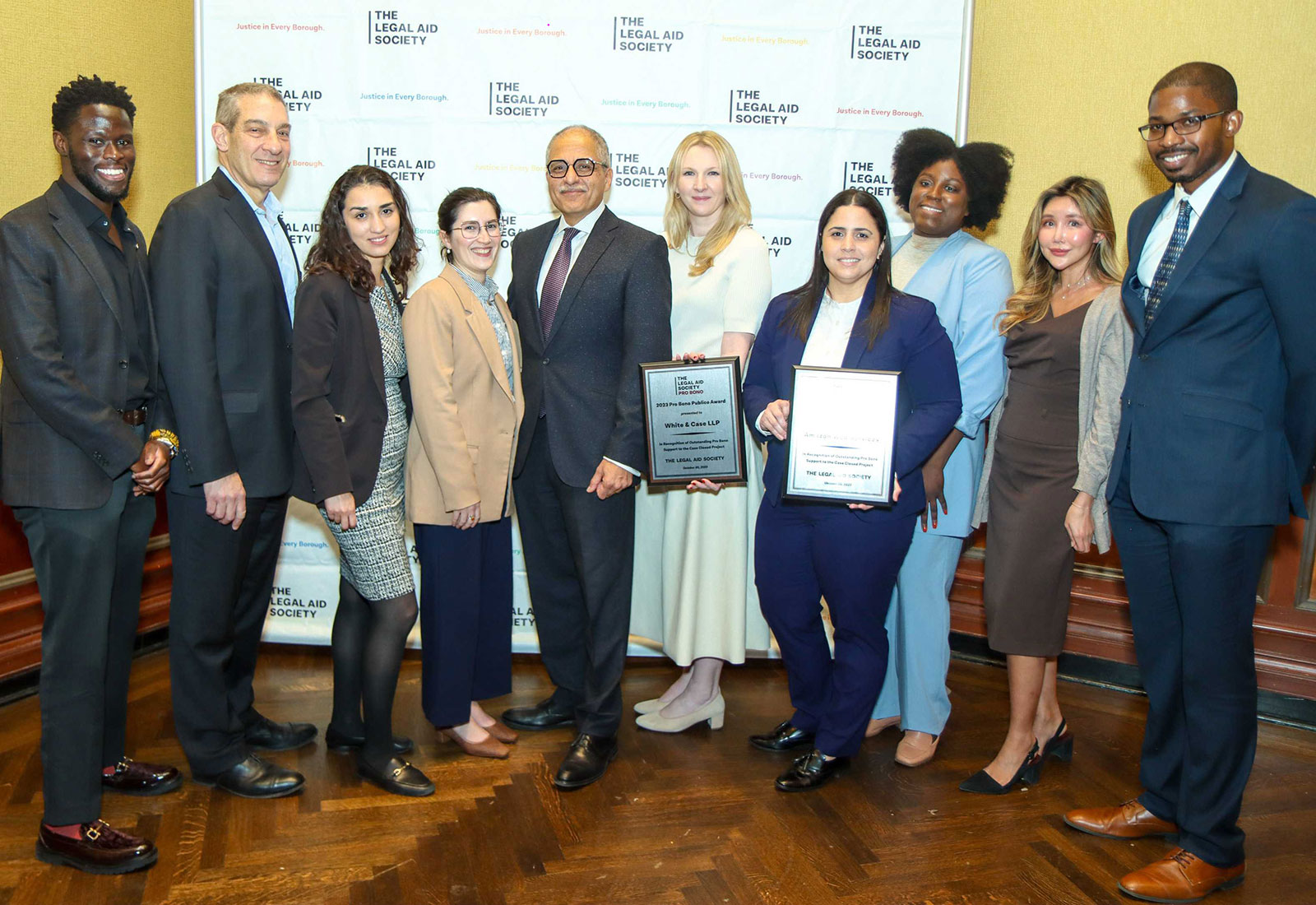 Nine White & Case and Amazon lawyers pose with the Honorable Rowan D. Wilson, Chief Judge of the New York Court of Appeals, at the Legal Aid Society’s 2023 Pro Bono Publico Awards, where the Firm and Amazon won an Outstanding Service award. Standing in a semi-circle, from left to right: Steven Kobby Lartey (Amazon), Steven Lutt, Sylvia Precht, Hannah Rubashkin, Judge Wilson (presenter), Claire DeLelle, Eva María González (Amazon), Jasmine Armand, Jennifer Lee, Travis Long (Amazon).