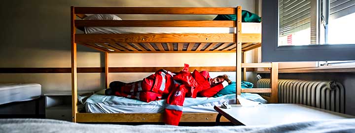 A photo of a Red Cross volunteer resting on a bottom bunk in a dormitory during Easter Sunday at the organization's headquarters in Turin, Italy.