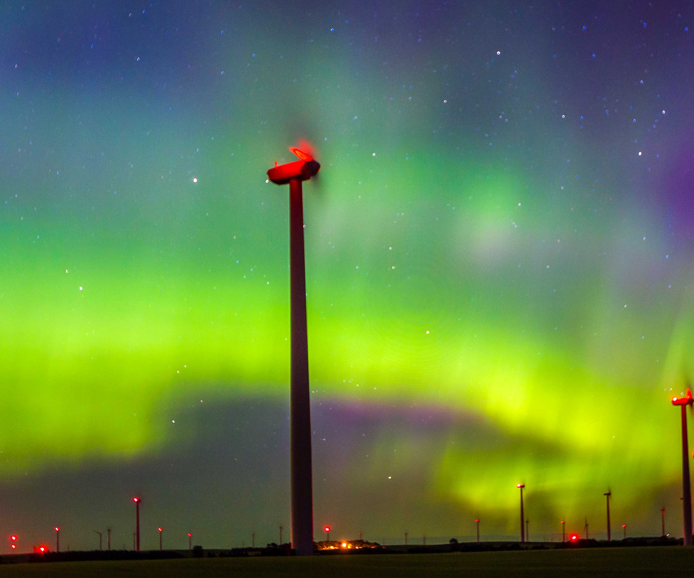 The Northern Lights appear in the sky over a wind farm near Bismarck, ND. © Mike Theiss