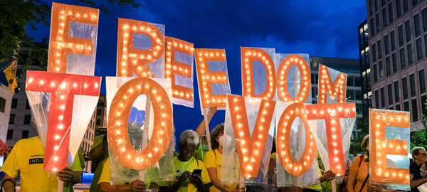 Voting rights activists during a rally at Black Lives Matter Plaza in Washington, DC hold up large individual orange letters emblazoned with light bulbs that spell out the words Freedom to Vote.