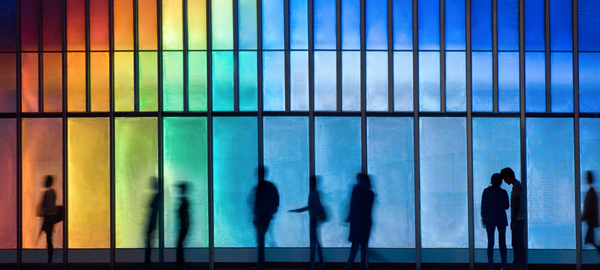 Silhouettes of individuals walking past an LED-lit building façade in Hong Kong, China