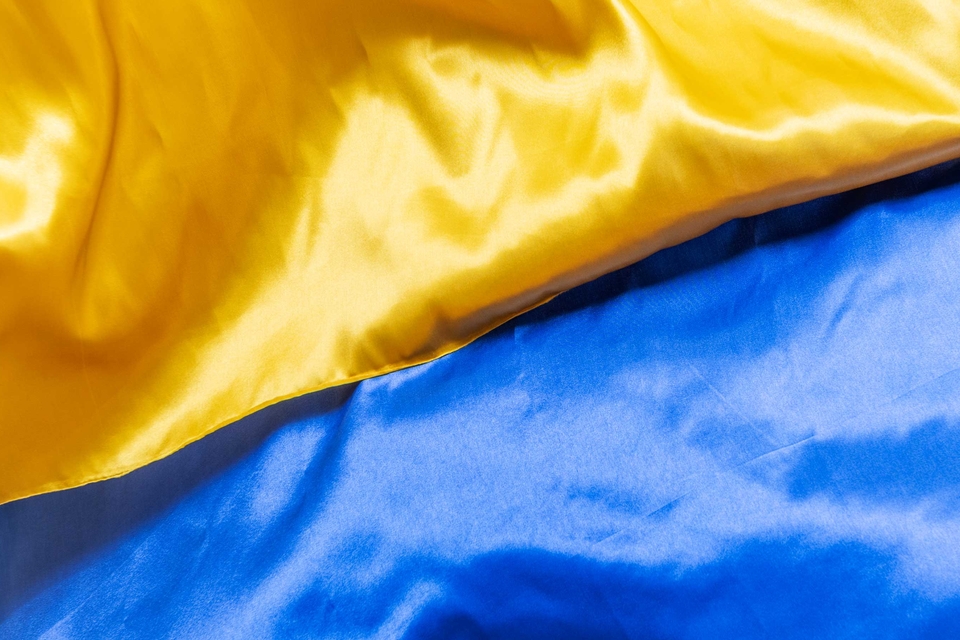 Two satin fabrics—one yellow and one blue, matching the colors of the Ukrainian flag—are partially sewn together.