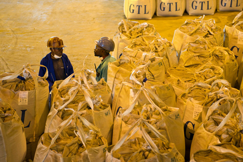  Congolese workers stand beside bags of a mixture of cobalt and copper