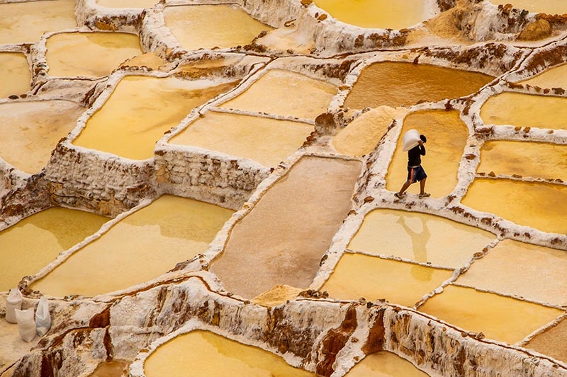 worker mining in yellow salt flats in Peru