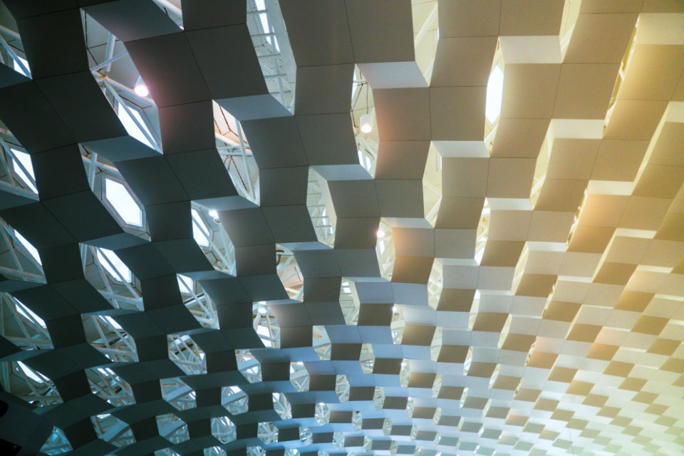 A closeup shows architectural details of a ceiling in Shanghai. It appears as if three-dimensional columns of blocks hang from the ceiling and reflect light. 