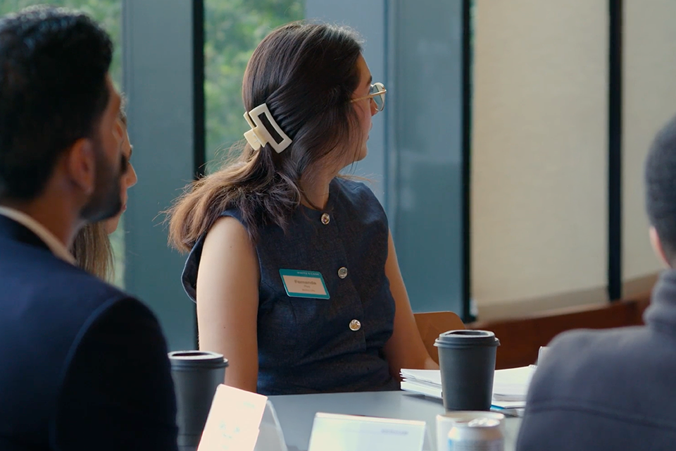 Four law firm associates seated are at a table and looking away from the camera