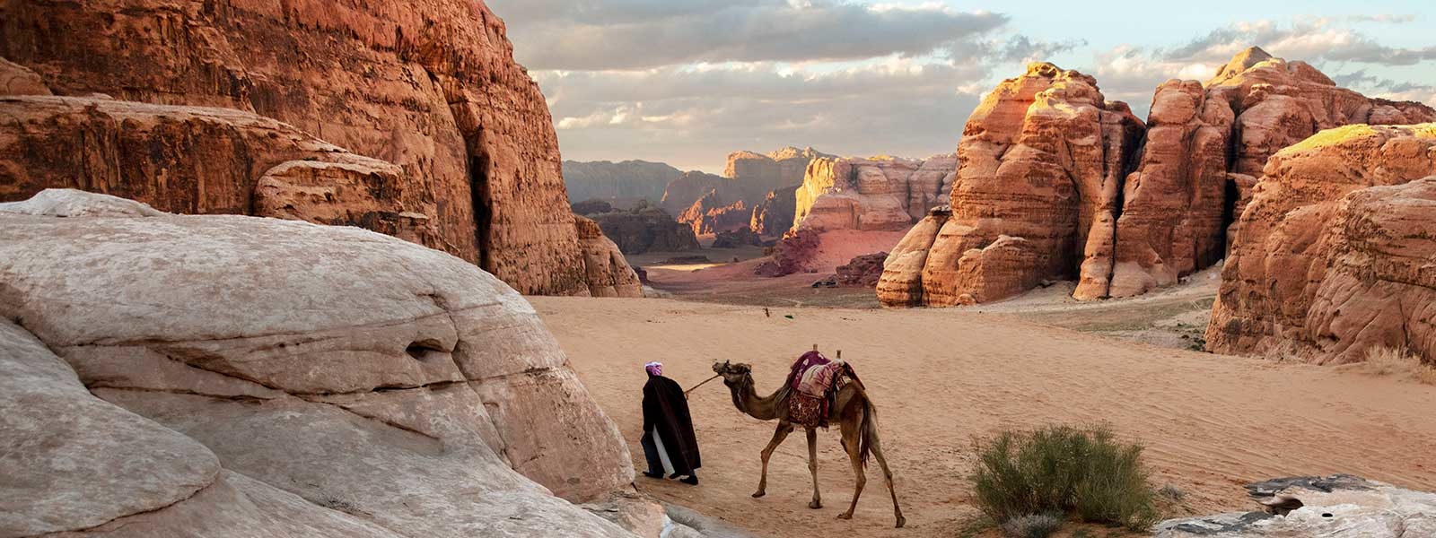 Man walking camel in desert