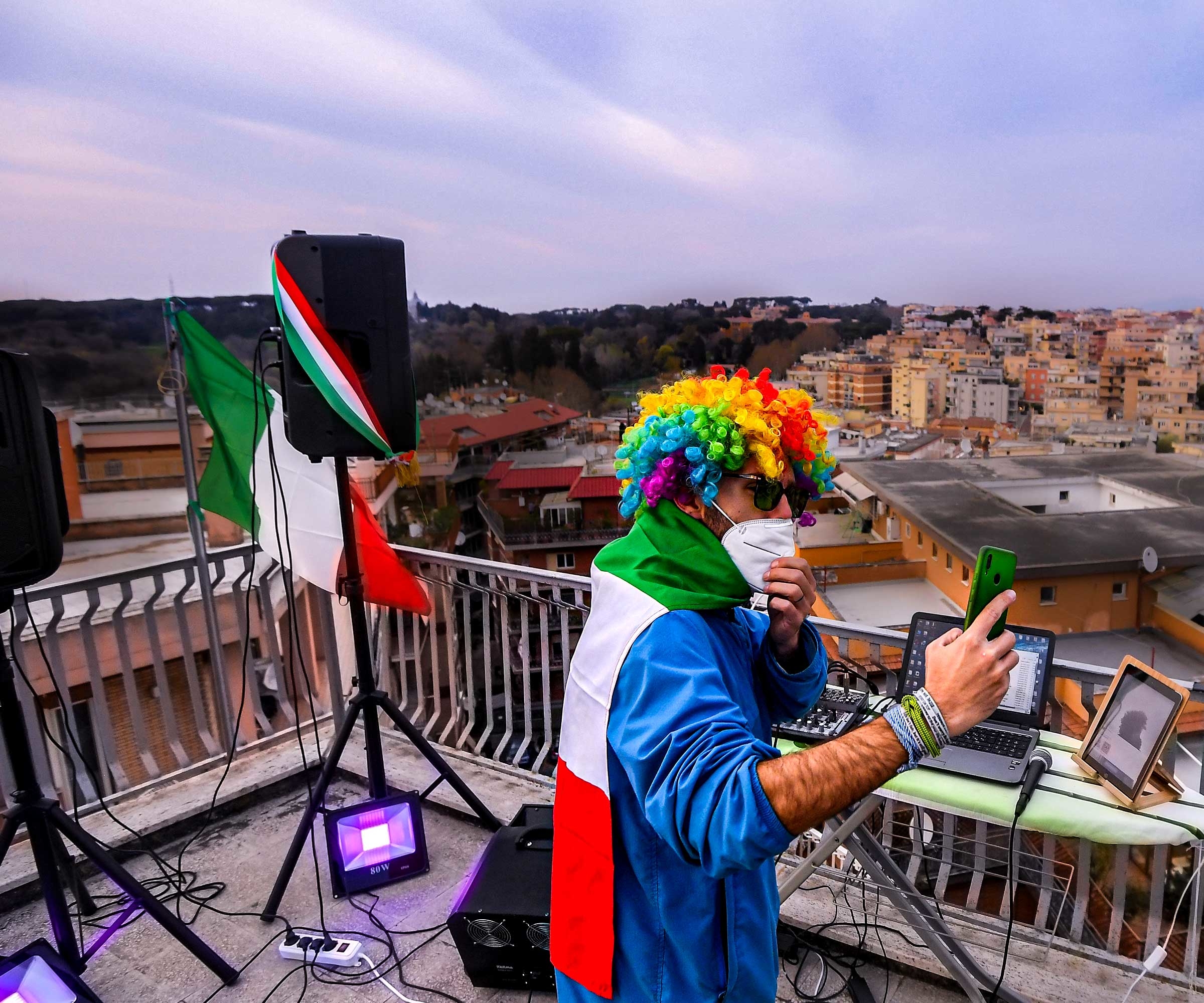 In Rome, a DJ prepares to entertain his neighbors from a rooftop during the pandemic. © Alberto Lingria/Reuters