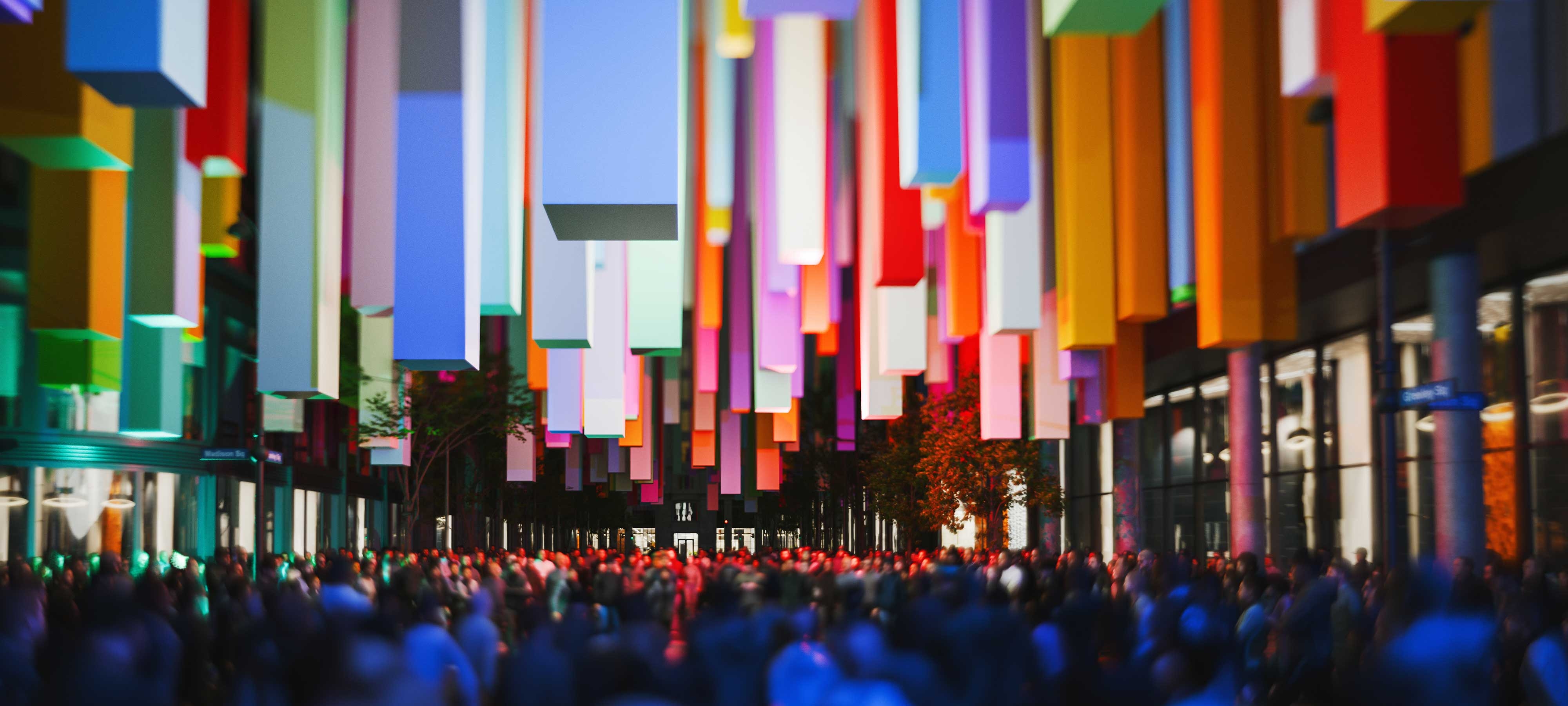 Multi-colored rectangular objects are suspended in the air above a crowd of people on a city street.